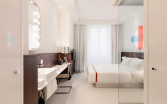 Modernes Hotelzimmer mit Doppelbett, Spiegel und minimalistischem Design.
