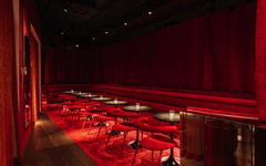 Elegante Hotelbar mit roten Vorhängen, Tischen und Stühlen.