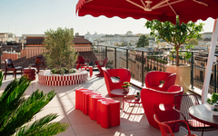 Rooftop-Terrasse mit roten Möbeln und Blick auf Rom.