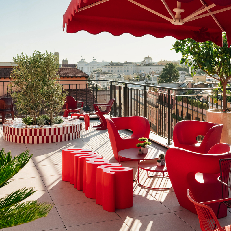 Rooftop-Terrasse mit roten Möbeln und Blick auf Rom.