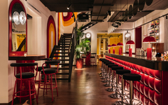 Moderne Hotelbar mit roten Hockern und stilvoller Beleuchtung.