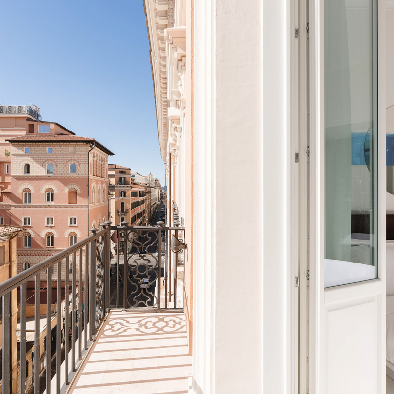 Balkon mit Blick auf römische Gebäude bei sonnigem Wetter.