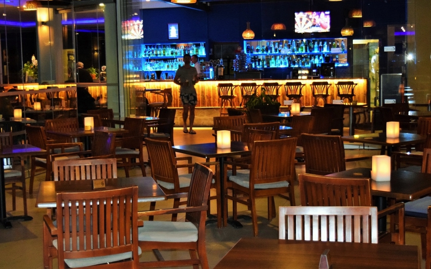 Barbereich mit Holzmöbeln und beleuchtetem Tresen im Hotel Theo Sunset Bay auf Zypern.