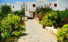 Steinweg im Garten eines Hotels mit weißen Gebäuden im Hintergrund.