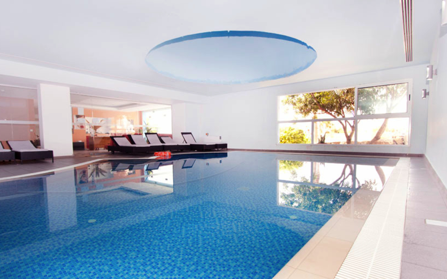 Innenpool mit Liegen in einem hellen Raum im Hotel auf Zypern.