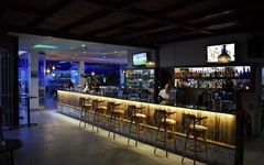 Innenansicht einer stilvollen Bar mit Hockern und beleuchteter Theke.