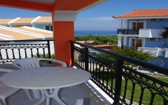 Balkon mit Tisch und Stühlen, Blick auf Gebäude und Meer im Hintergrund.