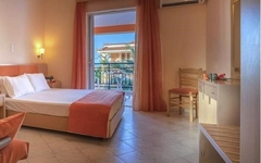 Helles Hotelzimmer mit Doppelbett, Schminktisch und Balkon mit Ausblick.