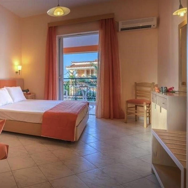 Helles Hotelzimmer mit Doppelbett, Schminktisch und Balkon mit Ausblick.