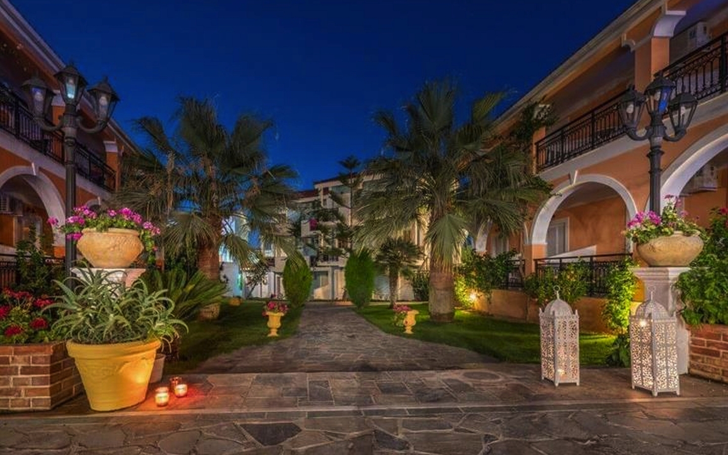 Hof eines Hotels mit Palmen und Laternen in Abendstimmung.