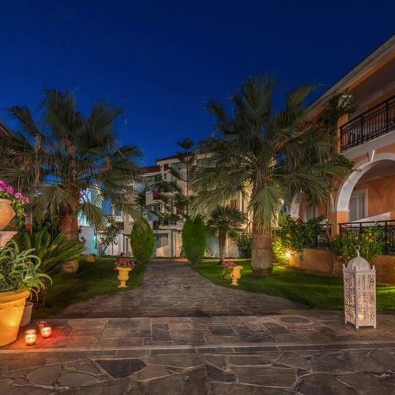 Hof eines Hotels mit Palmen und Laternen in Abendstimmung.