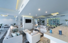 Helle Lobby eines Hotels mit modernen weißen Sofas und dekorativen Regalen.