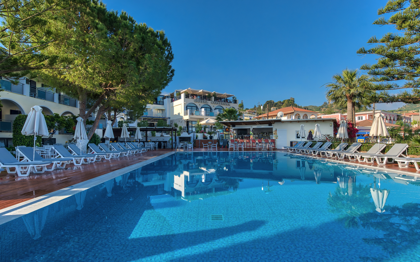 Poolbereich eines Hotels auf Zakynthos, Griechenland mit Liegestühlen und Sonnenschirmen.