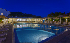 Außenpool im Hotel Cavo d'Oro bei Nacht, umgeben von Sonnenliegen und Schirmen.