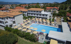 Hotelanlage mit Pool und Sonnenliegen in Griechenland, umgeben von grüner Landschaft.