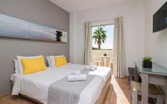 Helles Hotelzimmer mit Doppelbett, Balkon, Palmenblick.