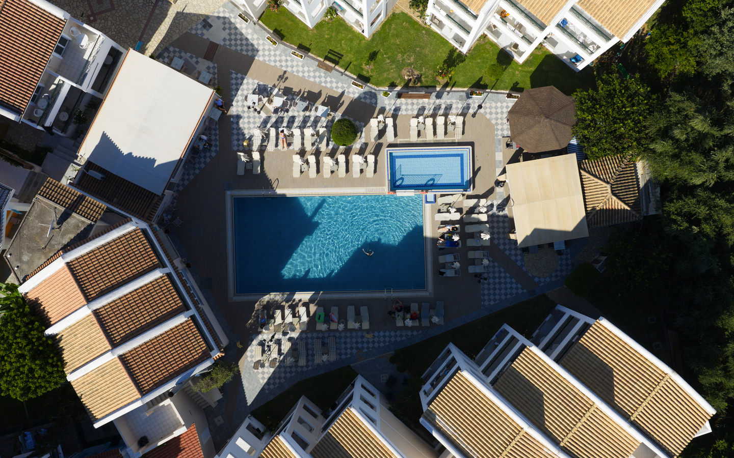 Luftaufnahme eines Hotelkomplexes mit zwei Pools und umliegenden Gebäuden.