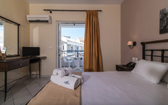 Hotelzimmer mit Bett, Schreibtisch, Klimaanlage und Balkonansicht in Griechenland.