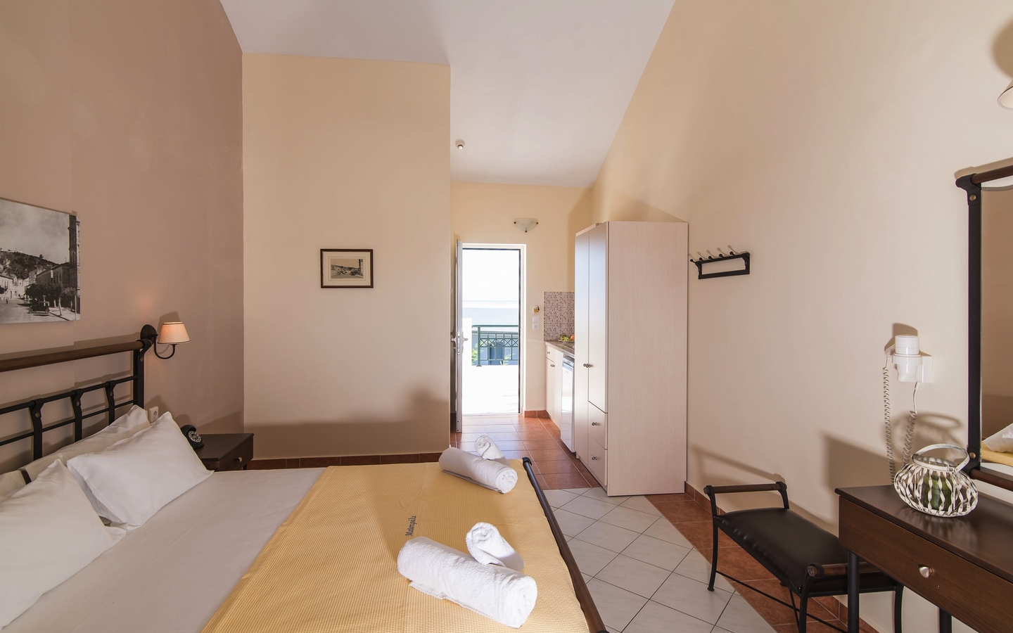 Helles Hotelzimmer mit Doppelbett, Schreibtisch und Blick auf den Balkon.