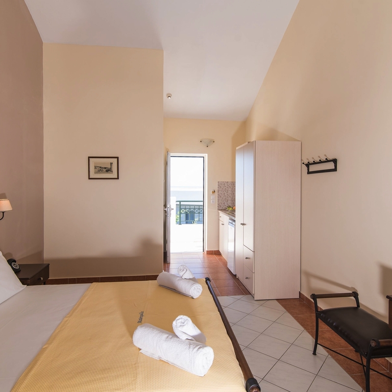 Helles Hotelzimmer mit Doppelbett, Schreibtisch und Blick auf den Balkon.