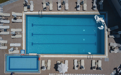 Luftaufnahme eines großen rechteckigen Swimmingpools mit Liegestühlen.
