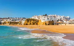 Küstenstadt mit weißen Häusern und Sandstrand am blauen Meer.