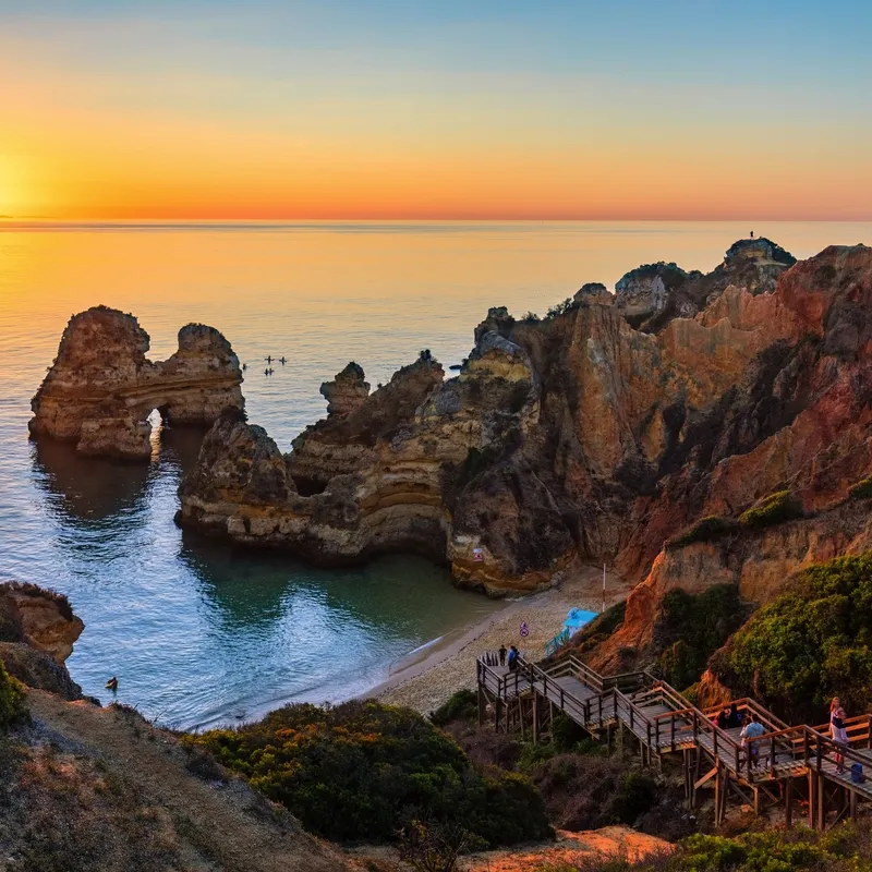 Klippen und Treppen am Camilo-Strand in Algarve bei Sonnenuntergang
