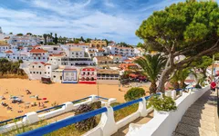 Strandpromenade mit weißen Gebäuden und Menschen, die den Strand genießen.