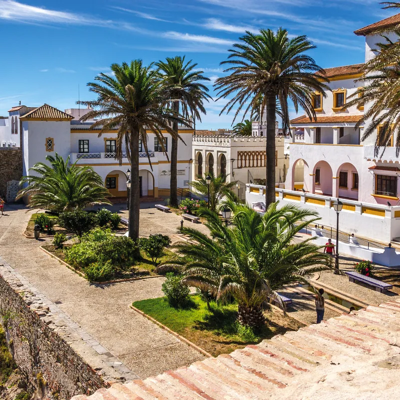 Platz mit Palmen und historischen Gebäuden in Tarifa, Spanien bei sonnigem Wetter.