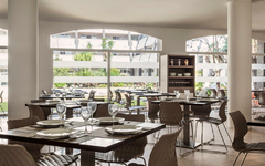 Restaurantbereich eines Hotels mit gedeckten Tischen und modernen Stühlen.