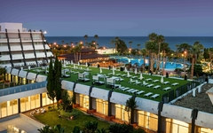 Hotel mit Pool und Garten an der Küste bei Sonnenuntergang.