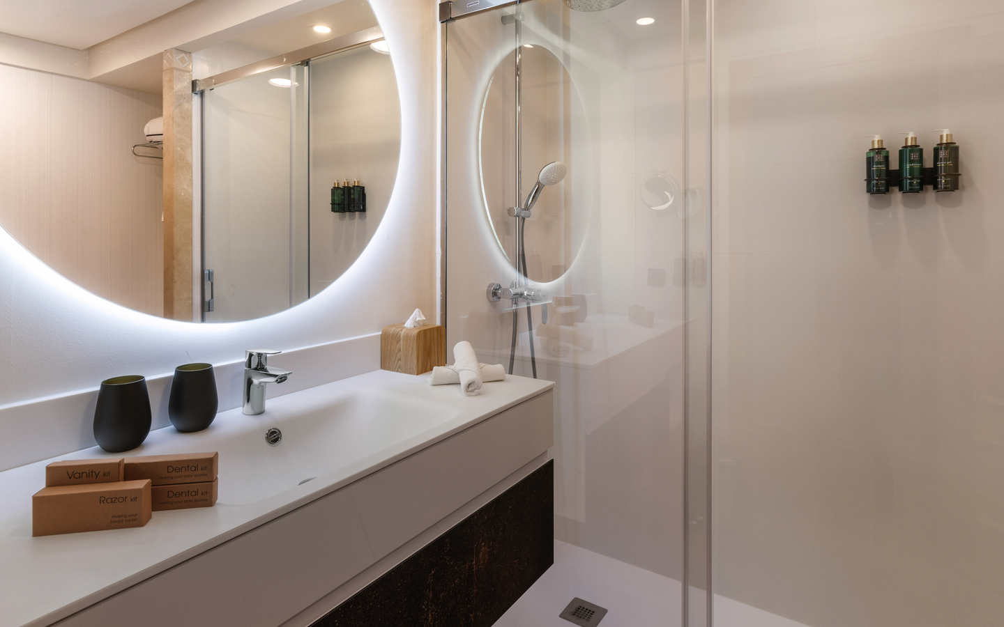 Modernes Hotelbadezimmer mit beleuchtetem Spiegel und Dusche.