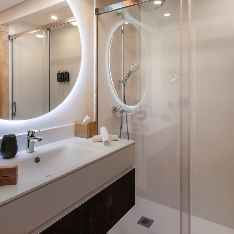 Modernes Hotelbadezimmer mit beleuchtetem Spiegel und Dusche.