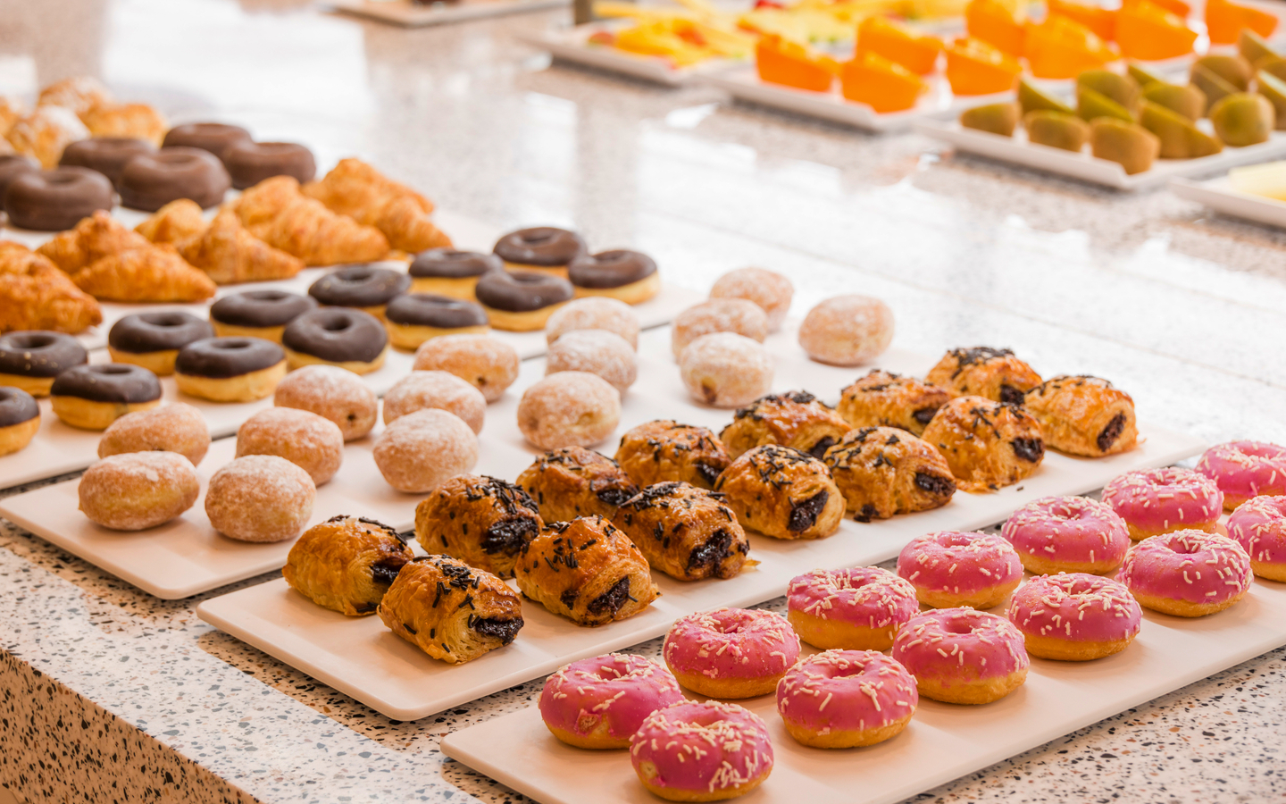 Ein Buffet mit verschiedenen Gebäcksorten, darunter Donuts und Croissants.
