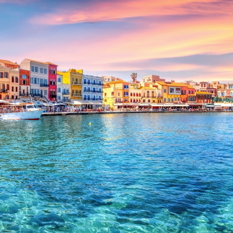 Traditioneller Hafen von Chania, Kreta bei Sonnenuntergang mit bunten Gebäuden.