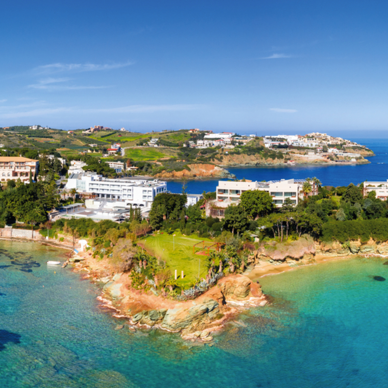 Küste von Agia Pelagia auf Kreta mit klarem blauem Meer und Häusern.