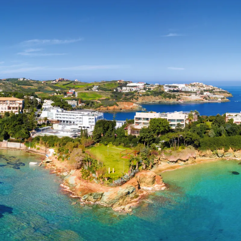 Küste von Agia Pelagia auf Kreta mit klarem blauem Meer und Häusern.