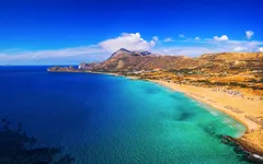 Strand von Falasarna auf Kreta, Griechenland, mit klarem blauem Wasser und Hügel im Hintergrund.
