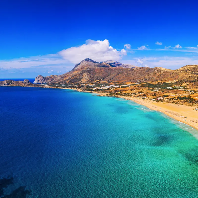 Strand von Falasarna auf Kreta, Griechenland, mit klarem blauem Wasser und Hügel im Hintergrund.