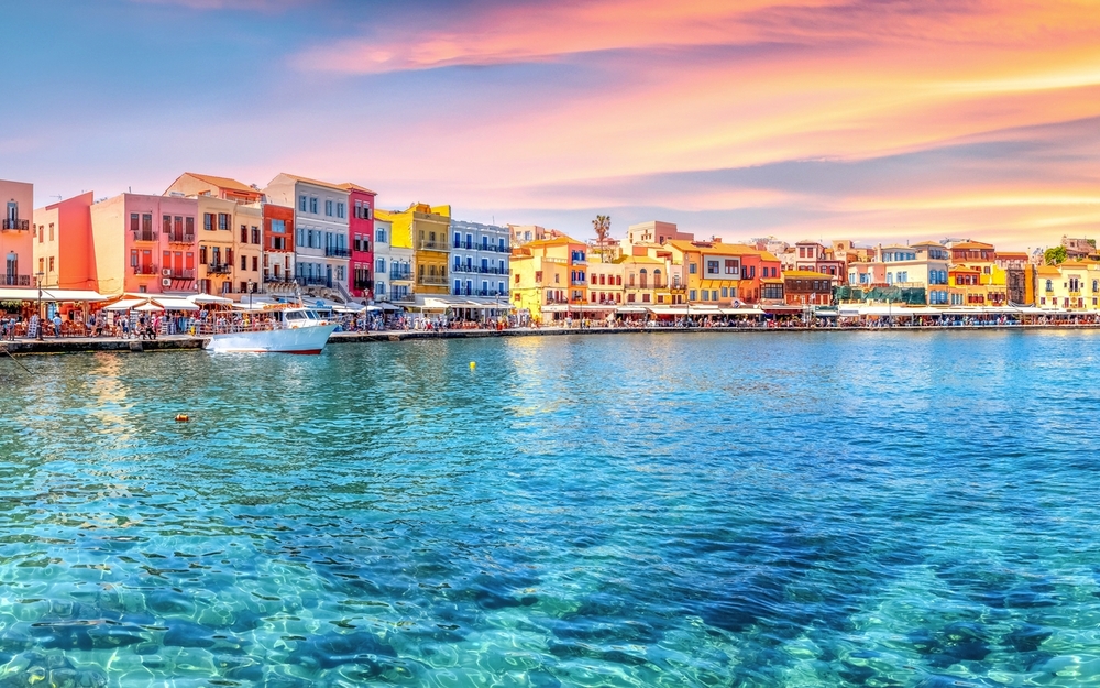 Traditioneller Hafen von Chania, Kreta bei Sonnenuntergang mit bunten Gebäuden.