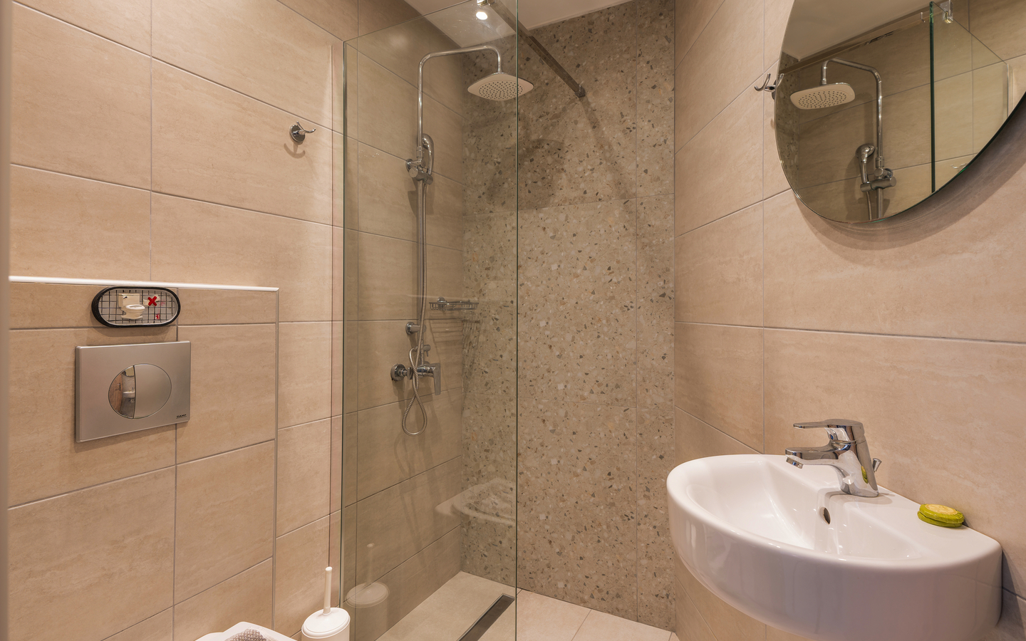 Modernes Badezimmer mit Dusche, rundem Spiegel und Waschbecken.