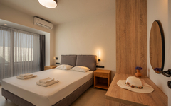 Modernes Hotelzimmer mit Doppelbett und Balkonaussicht.