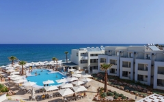 Hotelanlage am Strand mit Pool, Liegen und Meerblick bei schönem Wetter.