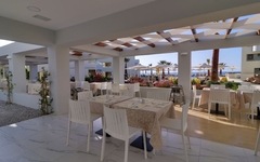 Restaurantbereich eines Hotels mit Tischen und Meerblick im Freien.