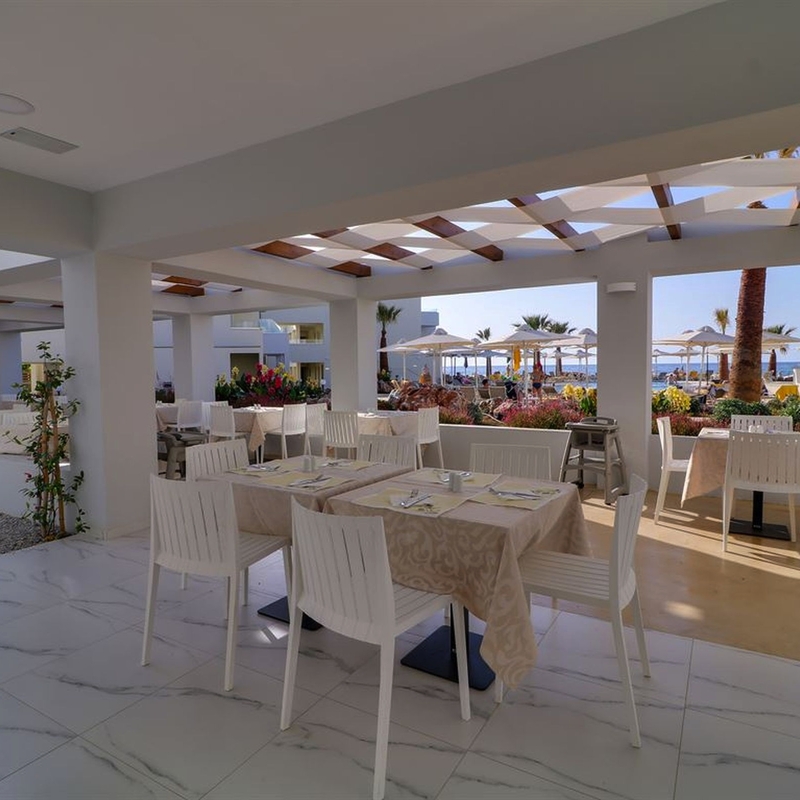 Restaurantbereich eines Hotels mit Tischen und Meerblick im Freien.