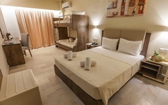 Hotelzimmer mit Doppel- und Etagenbett, modern eingerichtet, in warmen Farbtönen.