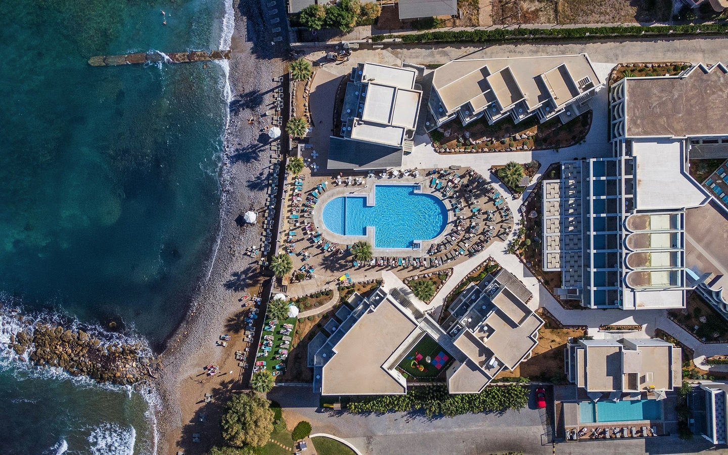 Luftaufnahme eines Strandhotels mit Pool in Kreta, direkt am Meer gelegen.