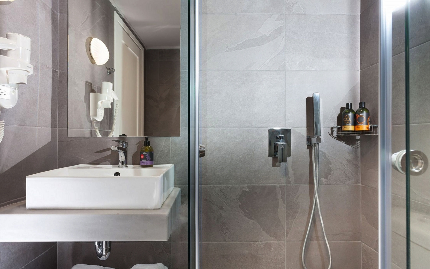 Modernes Badezimmer mit Dusche, Waschbecken und Ablage im Giannoulis Santa Marina Beach Hotel.