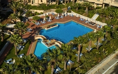 Poolbereich des Hotels Giannoulis Santa Marina Beach mit Liegestühlen und Palmen in Kreta.