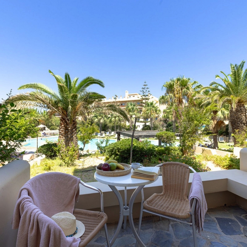 Terrasse mit Sitzmöbeln und Blick auf Garten mit Palmen